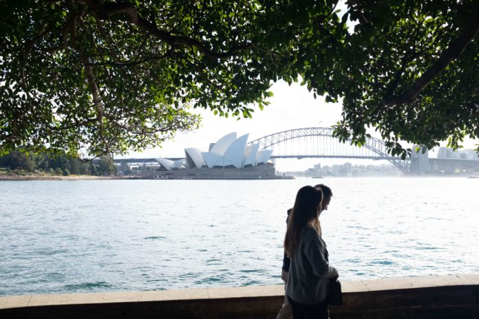 couple walking with views of the sydney opera house