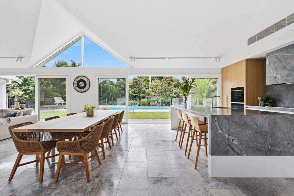 mount martha ultimate lifestyle home looking through the concreted living area out to the backyard and pool with high slanted ceilings and beams