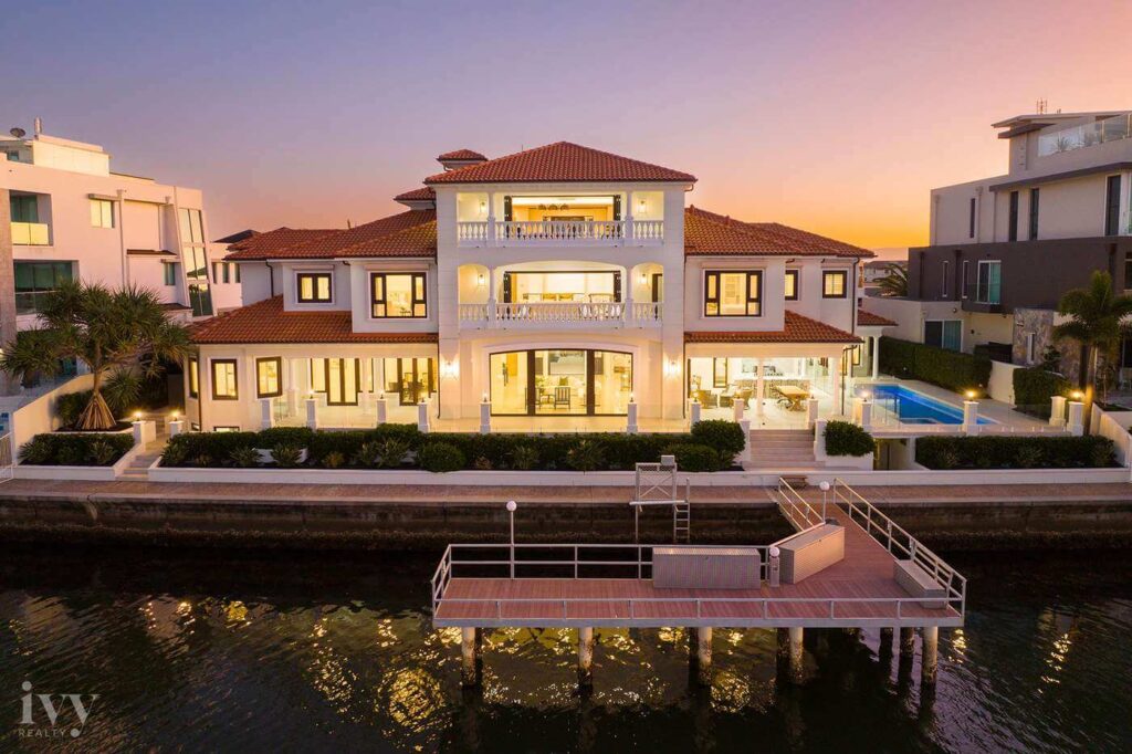 waterfront queensland property at sunset glowing with lights on reflecting off the water