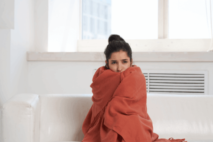 Woman hiding in orange blanket from the cold