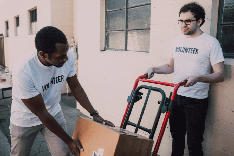 Two volunteers using a hand truck to move boxes