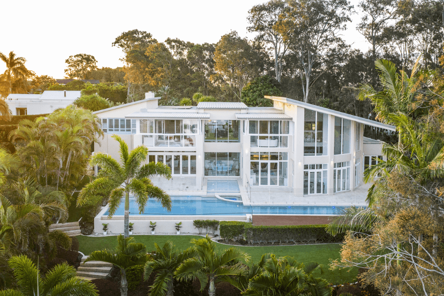 Large white home with big windows and pool along building length